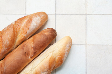 Fresh baguettes on white tile background