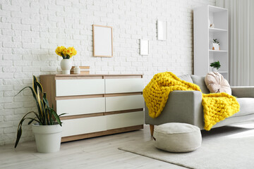 Interior of living room with sofa, commode and narcissus in vase
