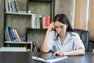 A woman is sitting at a desk with a tablet in front of her