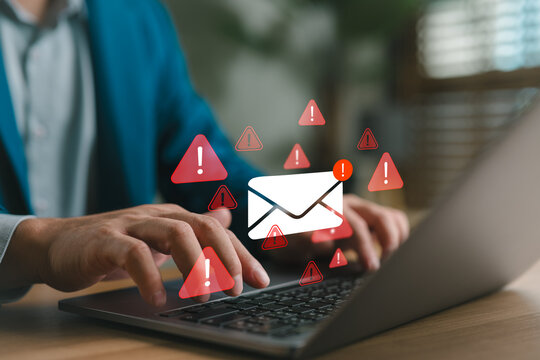 Businessman typing on laptop with warning email icons, representing email threat, phishing attack, malware, data breach, cybersecurity alert, scam message, spam risk, and online fraud protection. - Powered by Adobe