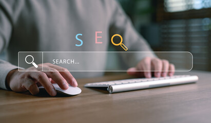 Hands using computer with SEO and search bar interface, representing search engine optimization,...