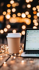 White disposable coffee cup and open laptop on wooden surface with bokeh background