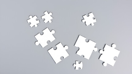 Naklejka premium White jigsaw puzzle pieces in disarray on a gray backdrop, difficult, unraveling, brain game, solution, jigsaw
