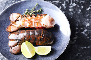 Raw lobster tails, lime and thyme on dark table, above view