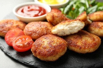 Tasty patties and tomato on grey table, closeup