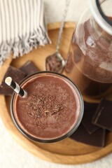 Tasty chocolate milk with shavings and pieces on white table, top view