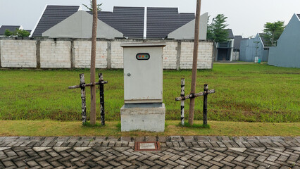 Electrical Utility Box in Grass Field Near Residential Area in wet pavement