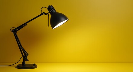 Black adjustable desk lamp shining bright on yellow background for study and work lighting solutions