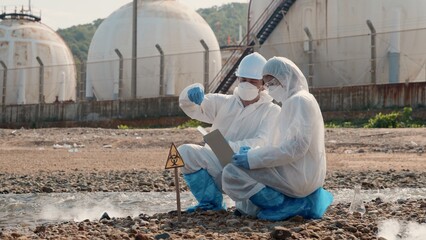 Biologist wear protective suit and mask collects sample of waste water from industry, problem...