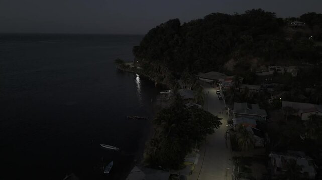Drone flies along coast of Punta Gorda after sunset in Roat&aacute;n, Honduras