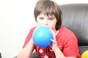 child blowing up balloons for birthday