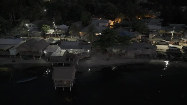 Drone flies to the right while facing the coast of Punta Gorda at night in Roat&aacute;n, Honduras