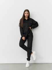Elegant model showcases modern fashion in minimalist studio setting with confidence