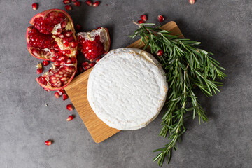 cheese, pomegranate and rosemary on wooden board
