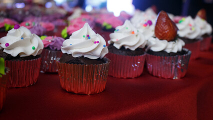 Coloridos cupcakes decorados con flores de crema sobre mesa de fiesta