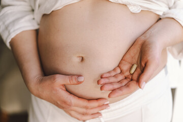 Pregnant young woman holding vitamins to maintain health of herself and her baby. Pregnancy and Health Concept