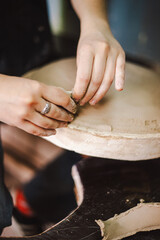 Hands skillfully shape a clay pot in a pottery studio. The workshop encourages creativity and focuses on teaching pottery techniques to beginners in a relaxed atmosphere.