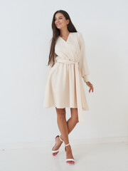 Elegant woman in stylish dress posing gracefully in a bright studio setting