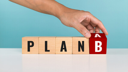 A man hand flipping wooden cube with the word PLAN A change to PLAN B on white background. Backup plan, daily plan and alternative plans concepts