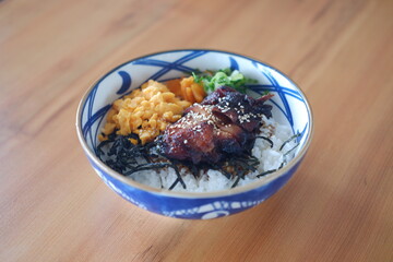 The bowl contains white steamed rice as the base, topped with various colorful ingredients