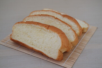 four slices of soft white bread neatly arranged on a bamboo mat