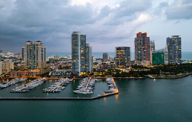 Fototapeta premium Miami Beach sunset aerial view. Downtown Miami skyline at dusk. South Beach neon lights at night. Tropical Miami waterfront panorama. Ocean Drive Art Deco buildings. Aerial view of Miami coastline.