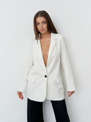 Model showcases stunning fashion in sleek white blazer and stylish pants in studio setting
