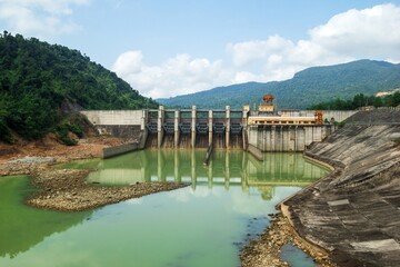 Concrete Hydroelectric Dam with Water Flowing Through Spillway Gates into River Below. Prao, Vietnam