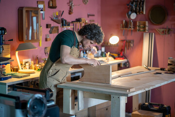 Professional meticulous carpenter exactly furniture assembling on workshop workbench using...