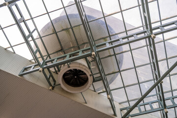 A low-angle view captures a large industrial fan installed beneath a metal grid ceiling. 