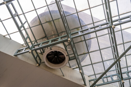 A low-angle view captures a large industrial fan installed beneath a metal grid ceiling. 
