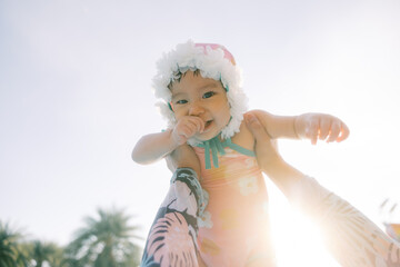 Happy Baby Being Held Outdoors with Sunlight and Tropical Background