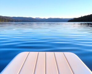 Obraz premium Calm lake view from a floating dock, mountains in the distance under a clear sky