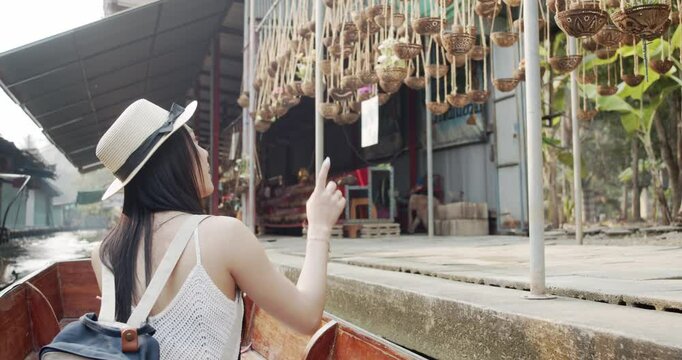 Young Asian tourist woman cheerful and happy to eat street food and sight seeing travel by boat along the canel at Damnoen Saduak Floating Market Thailand