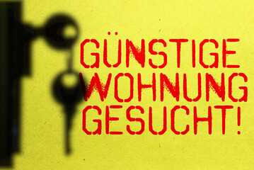 Ein Schlüssel und Slogan Günstige Wohnung Gesucht