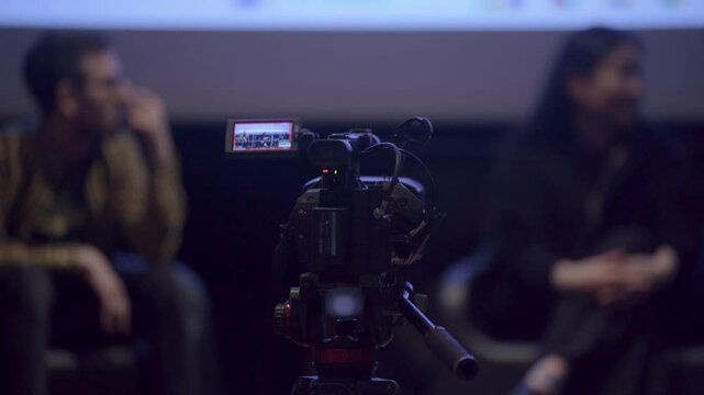 C&aacute;mara grabando una entrevista de dos personas en un escenario. Producci&oacute;n audiovisual, rodaje de entrevista, grabaci&oacute;n profesional, trabajo en set, medios y comunicaci&oacute;n.