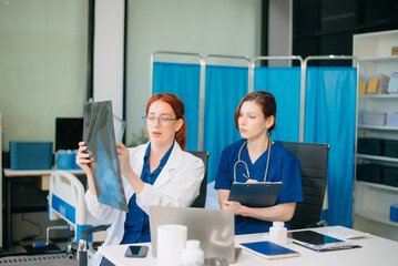 Doctor and nurse team using tablet to review medical results. Diverse healthcare professionals in modern hospital clinic