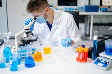 male scientist working with micro pipettes analyzing biochemical samples, advanced science chemical...