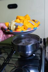 adding fresh vegetables to a pot of soup