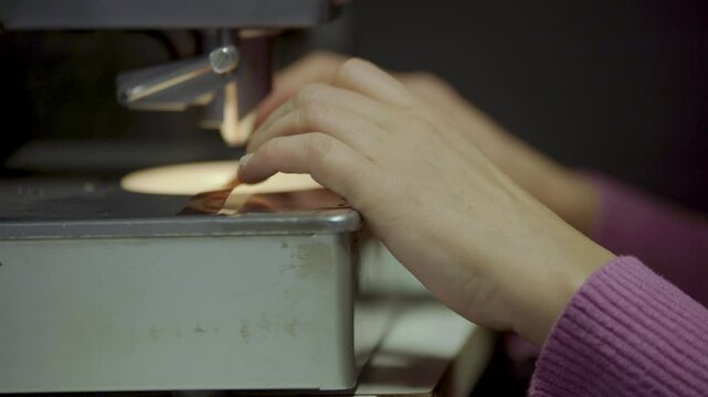 Persona manipulando pel&iacute;cula f&iacute;lmica de 16mm o 35mm en mesa de montaje f&iacute;sico. Montaje, Cine anal&oacute;gico, moviola, edici&oacute;n tradicional, cinematograf&iacute;a, historia del cine.
