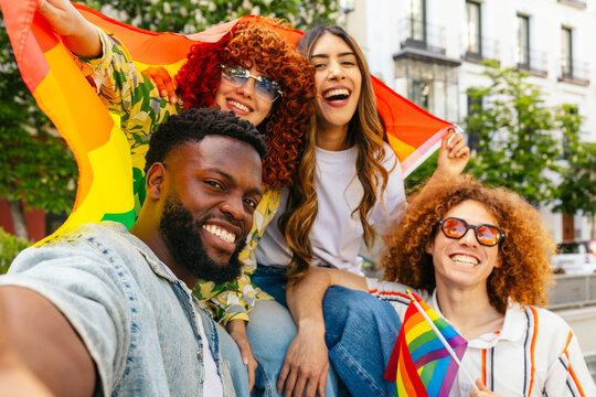 Multi ethnic friends taking selfie at lgbtqia plus pride parade celebrating with rainbow flag