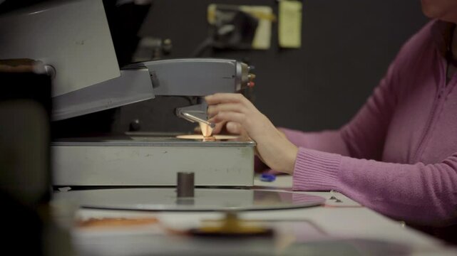 Persona manipulando pel&iacute;cula f&iacute;lmica de 16mm o 35mm en mesa de montaje f&iacute;sico. Montaje, Cine anal&oacute;gico, moviola, edici&oacute;n tradicional, cinematograf&iacute;a, historia del cine.