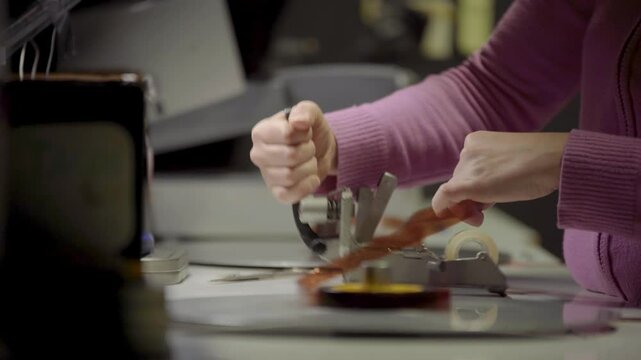 Persona manipulando pel&iacute;cula f&iacute;lmica de 16mm o 35mm en mesa de montaje f&iacute;sico. Montaje, Cine anal&oacute;gico, moviola, edici&oacute;n tradicional, cinematograf&iacute;a, historia del cine.