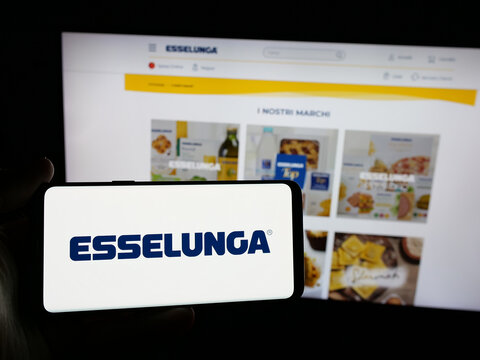 Stuttgart, Germany - 04-28-2025: Person holding smartphone with logo of Italian retail company Esselunga S.p.A. on screen in front of website. Focus on phone display.