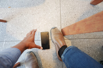 Person reaches for smartphone on the floor in a casual setting