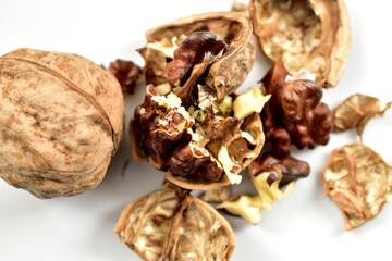 Cracked but unpeeled walnuts lie on a white background.
