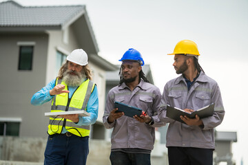 Three men in construction gear are walking down a street, each holding a clipboard. Scene is serious and focused, as the men are likely discussing plans or progress on a project
