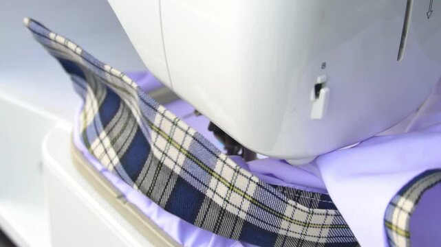 Automatic sewing machine that moves up and down to embroider threads on a white shirt. A white shirt that moves back and forth according to the commands of the automatic embroidery system.