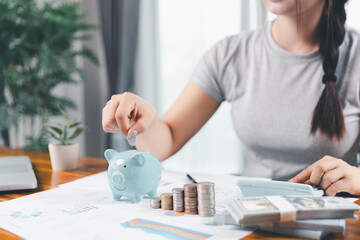 Businesswoman saving money with piggy bank and coins on desk, financial planning and investment...
