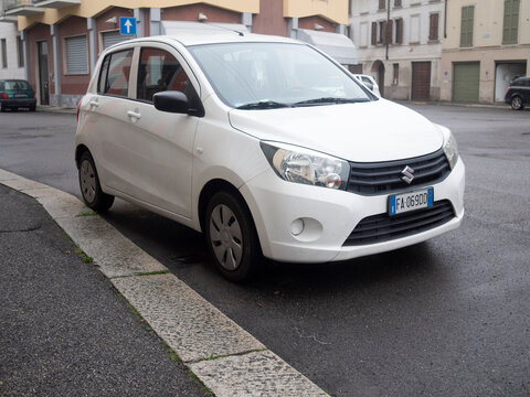 A White 2014 Suzuki Celerio GA Hatchback Car Parked on a City Street Showing the Front Grill Headlights Wheels and Overall Compact Car Design With a European License Plate